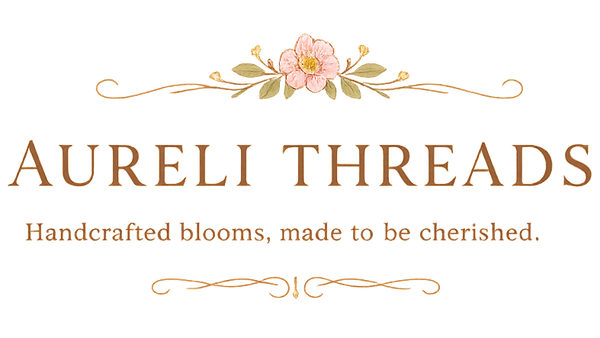 Aureli Threads logo centered on a white background, featuring a small pink flower with green leaves above the words 'AURELI THREADS' and the tagline 'Handcrafted blooms, made to be cherished.'.